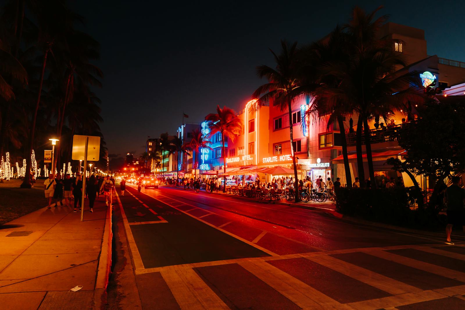 Neon-lit Art Deco buildings on a Miami Beach street at night, evoking the Vice City aesthetic