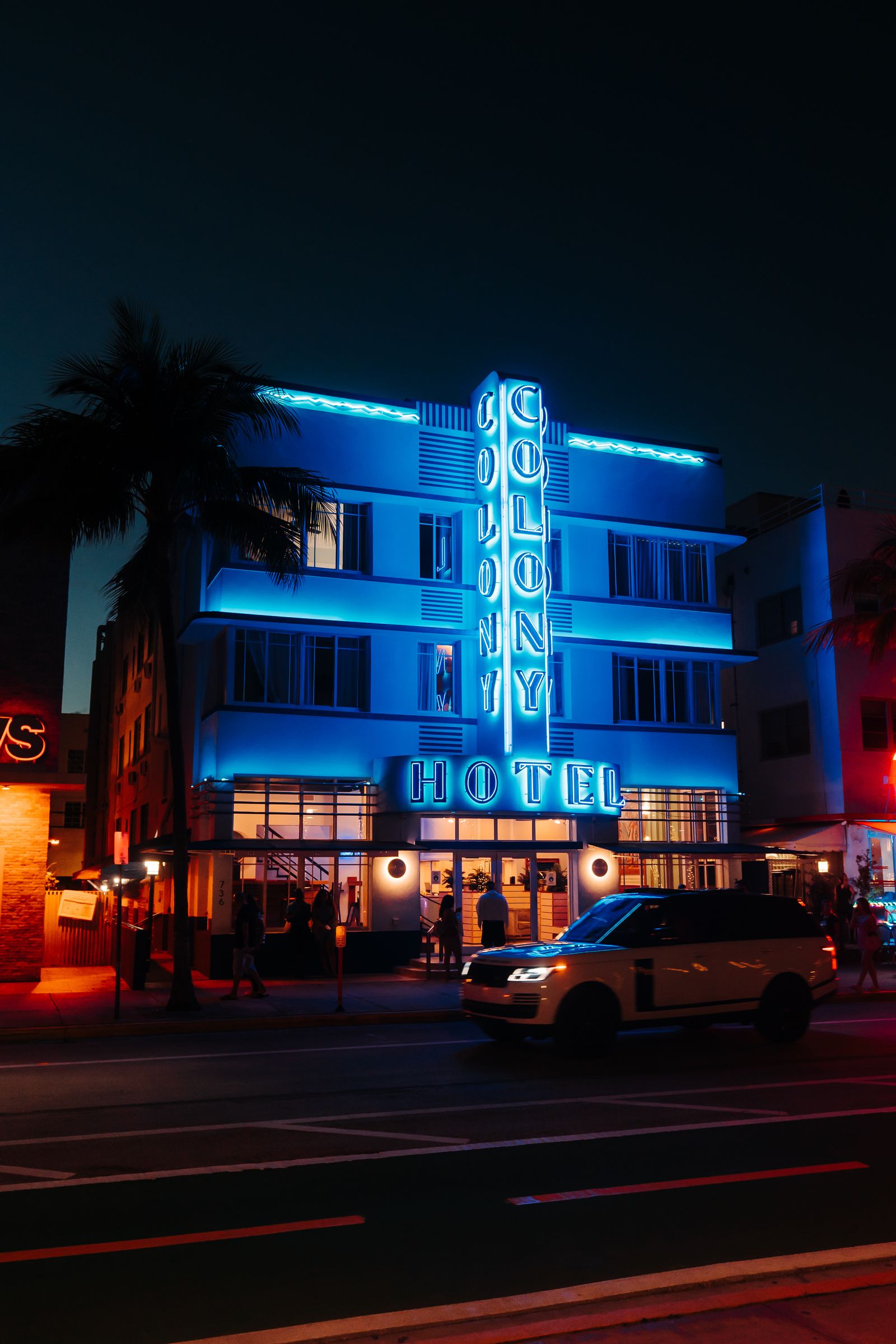 Illuminated vintage hotel with neon lights and a classic car at night