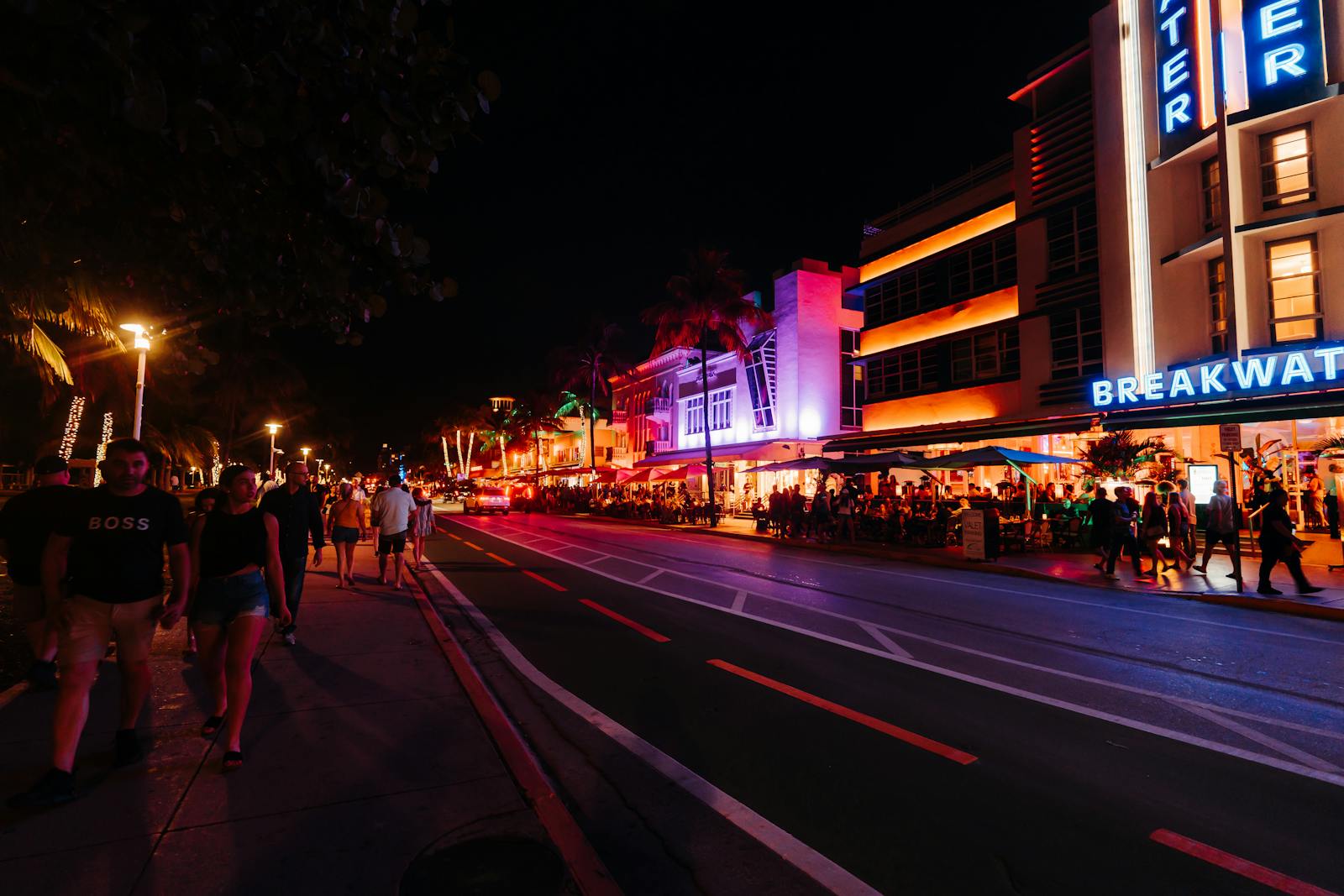 Crowded neon-lit Ocean Drive street at night with Art Deco hotels